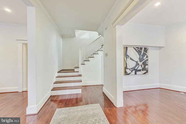 staircase with crown molding and wood-type flooring