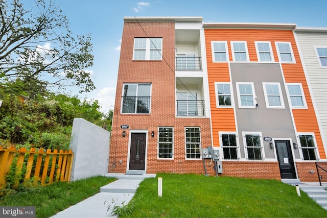 multi unit property featuring a front yard, fence, and brick siding