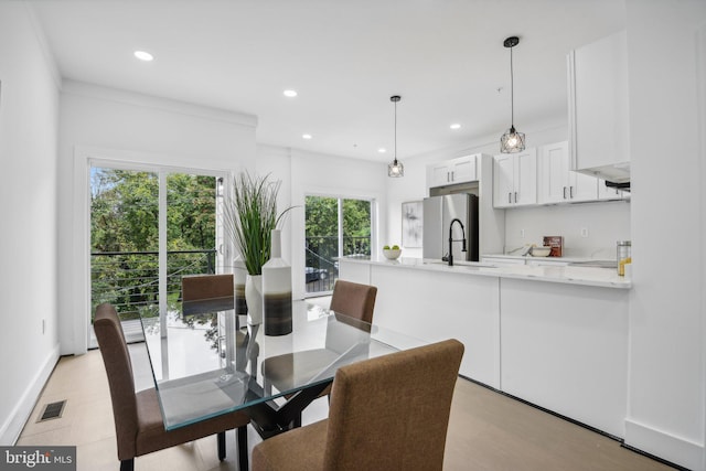 dining area with light hardwood / wood-style floors, ornamental molding, and sink