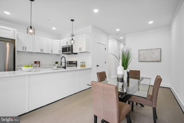 dining space with light hardwood / wood-style floors, crown molding, and sink