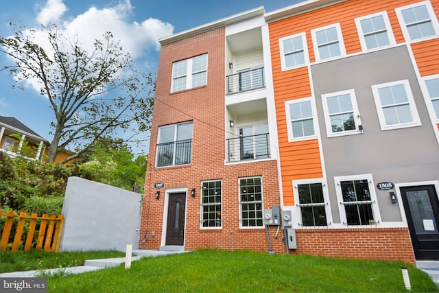 view of front facade with brick siding, a front lawn, and fence