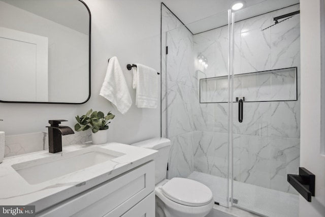 bathroom featuring a shower with shower door, vanity, and toilet