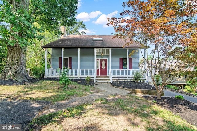 bungalow-style home featuring a porch, a chimney, and roof with shingles