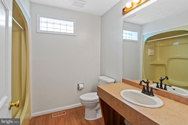 full bathroom with hardwood / wood-style flooring, a textured ceiling, shower / bathtub combination with curtain, toilet, and vanity