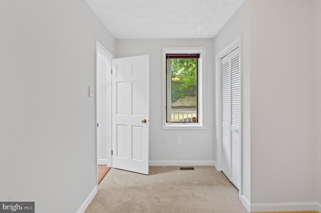 unfurnished bedroom featuring a closet, light colored carpet, and a textured ceiling