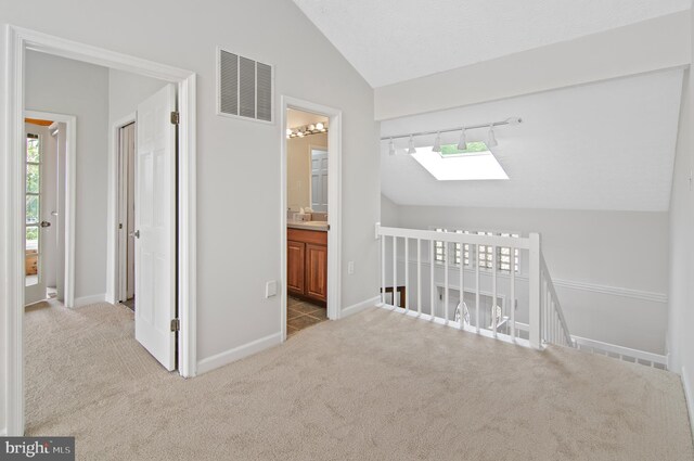 corridor featuring light carpet and lofted ceiling with skylight