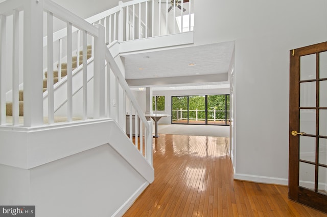 entryway featuring a high ceiling, hardwood / wood-style flooring, stairway, and baseboards