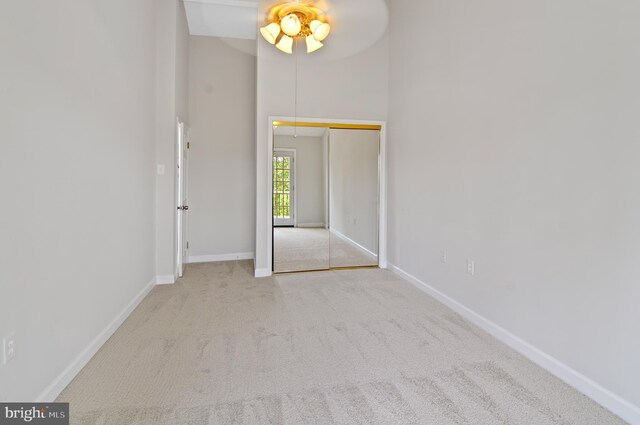 unfurnished bedroom with a high ceiling, a closet, and light colored carpet