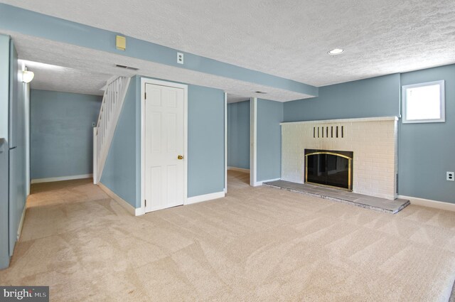 unfurnished living room featuring a textured ceiling, light carpet, and a brick fireplace