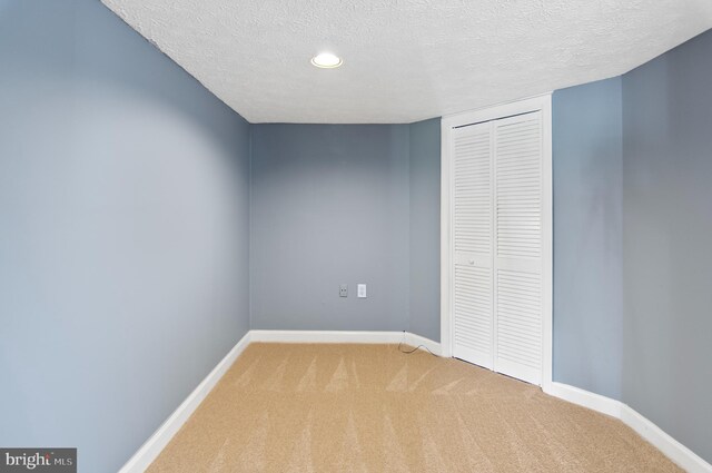 unfurnished bedroom featuring a textured ceiling, carpet, and a closet