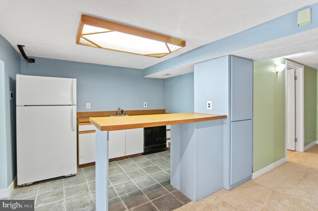 kitchen with white fridge, wood counters, kitchen peninsula, and a textured ceiling