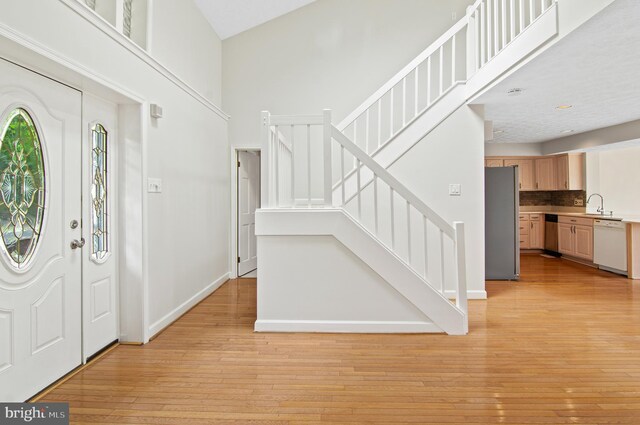 entryway featuring high vaulted ceiling, light hardwood / wood-style flooring, and sink