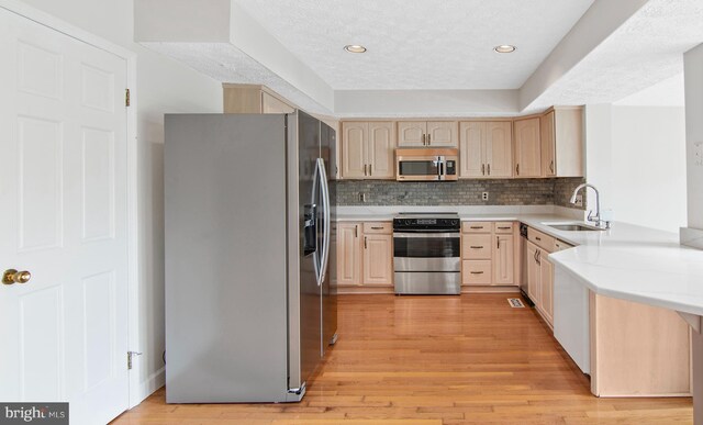 kitchen featuring a textured ceiling, appliances with stainless steel finishes, light hardwood / wood-style floors, sink, and light brown cabinets