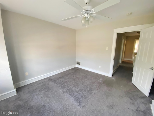 spare room featuring dark carpet and ceiling fan