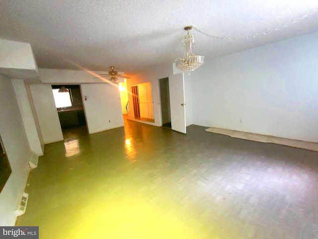 unfurnished room with ceiling fan with notable chandelier and a textured ceiling