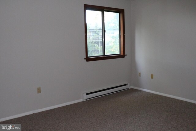 carpeted spare room with a baseboard heating unit