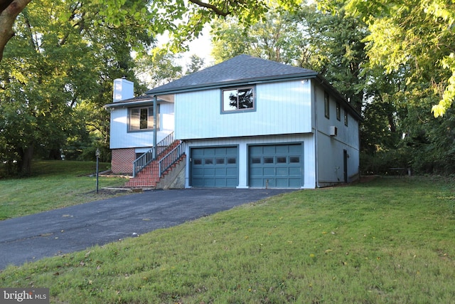 view of front of home with driveway, an attached garage, a chimney, stairs, and a front lawn