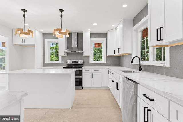 kitchen featuring wall chimney exhaust hood, white cabinetry, stainless steel appliances, and a wealth of natural light