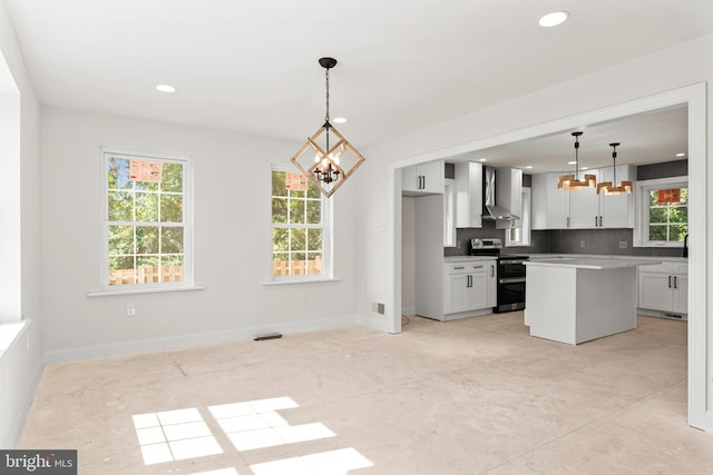 kitchen featuring stainless steel range with electric stovetop, white cabinetry, decorative light fixtures, and wall chimney range hood