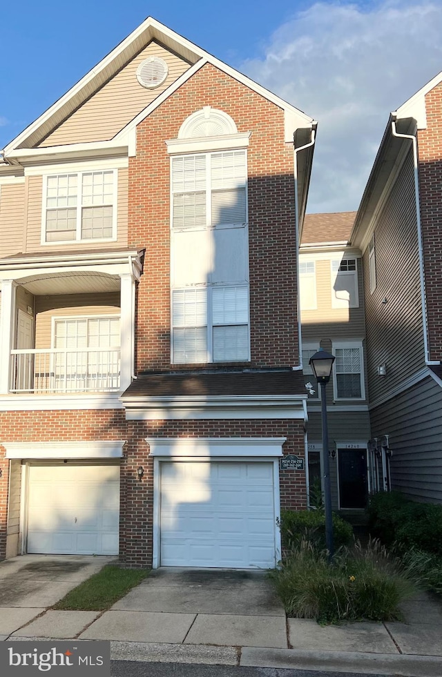 multi unit property featuring brick siding, driveway, and a garage