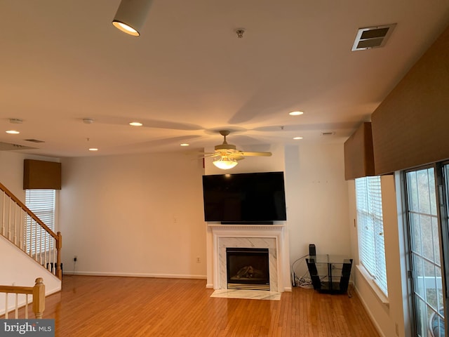 unfurnished living room featuring a high end fireplace, light hardwood / wood-style flooring, and ceiling fan