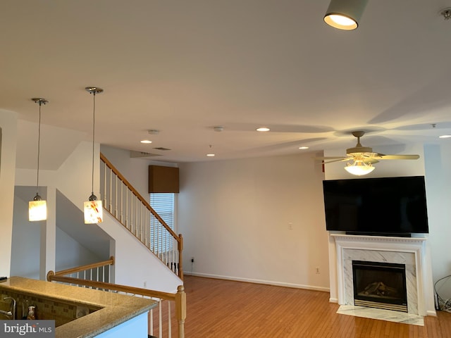 living room featuring light hardwood / wood-style flooring, a premium fireplace, and ceiling fan