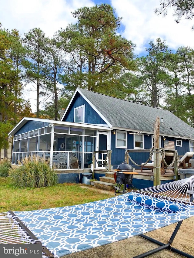 back of house featuring a wooden deck, roof with shingles, and a sunroom