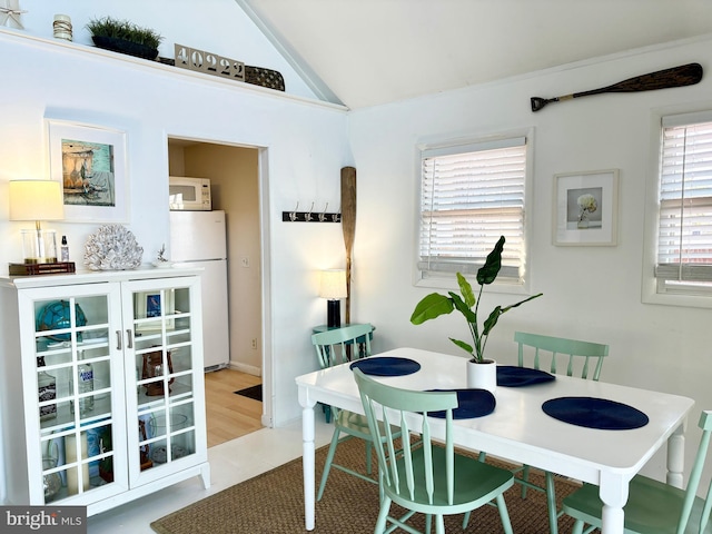 dining area with light tile patterned floors and lofted ceiling