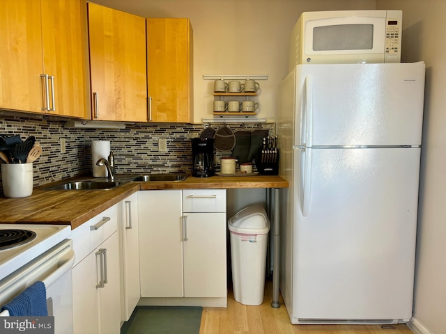 kitchen featuring white appliances, light wood-style flooring, butcher block countertops, a sink, and backsplash