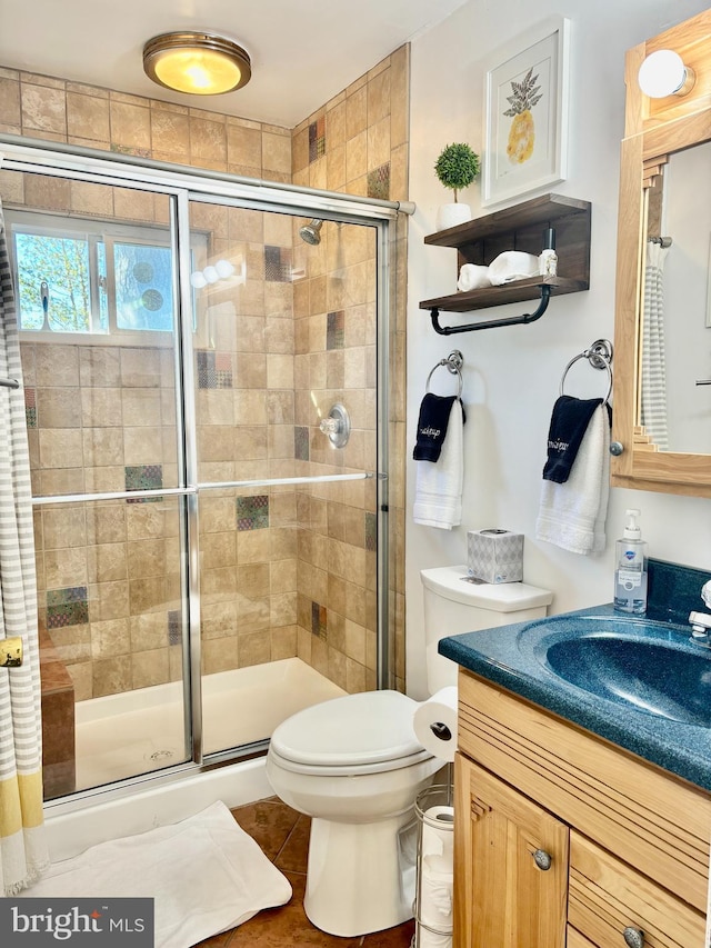 bathroom featuring tile patterned flooring, vanity, toilet, and a shower with shower door