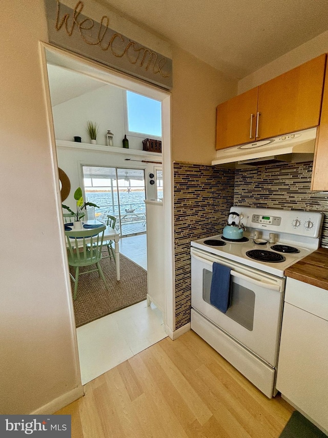 kitchen featuring under cabinet range hood, light wood-type flooring, decorative backsplash, and white electric range oven