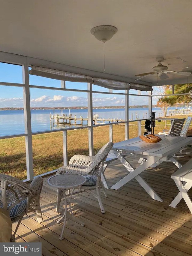 sunroom / solarium with a healthy amount of sunlight, ceiling fan, and a water view