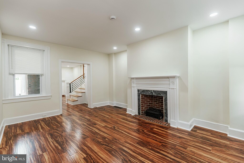 unfurnished living room with dark wood-type flooring and a fireplace