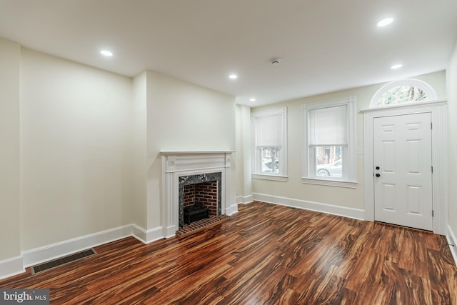 unfurnished living room featuring a wealth of natural light, dark hardwood / wood-style floors, and a premium fireplace