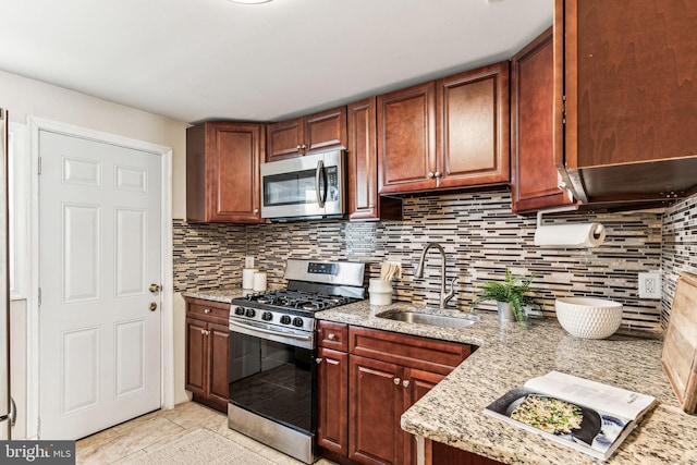 kitchen featuring light stone countertops, stainless steel appliances, decorative backsplash, and sink