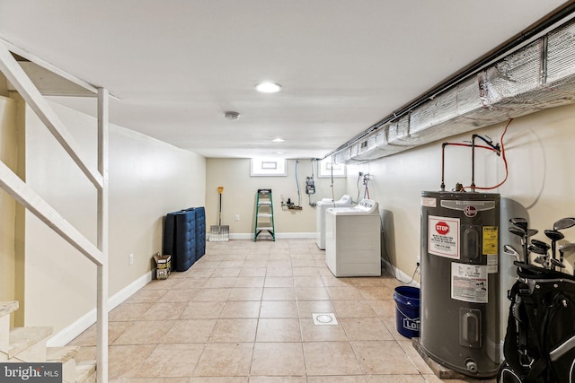 basement featuring light tile patterned floors, washing machine and clothes dryer, and electric water heater