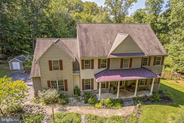 view of front of property with a garage, a patio, a front yard, an outdoor living space, and an outbuilding