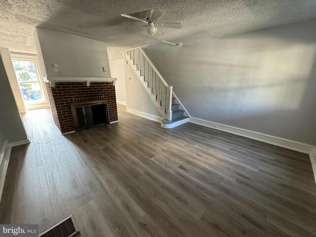 unfurnished living room with a fireplace, a textured ceiling, ceiling fan, and dark hardwood / wood-style floors