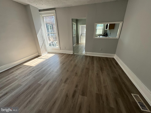 unfurnished living room featuring a textured ceiling and dark wood-type flooring