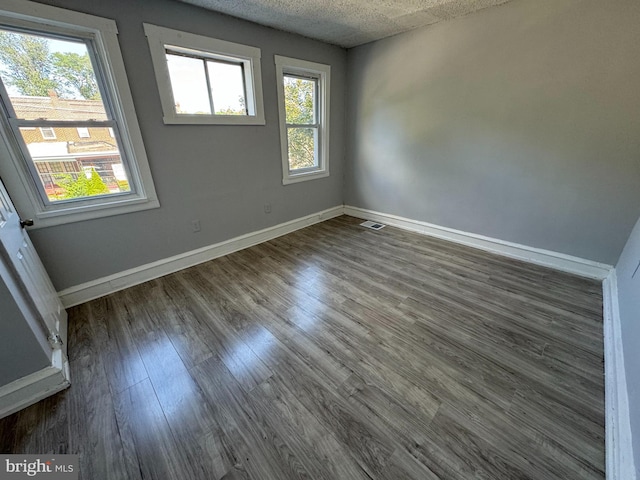 spare room featuring a textured ceiling and dark hardwood / wood-style floors