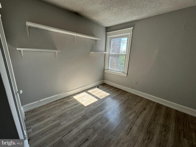 spare room featuring hardwood / wood-style flooring and a textured ceiling