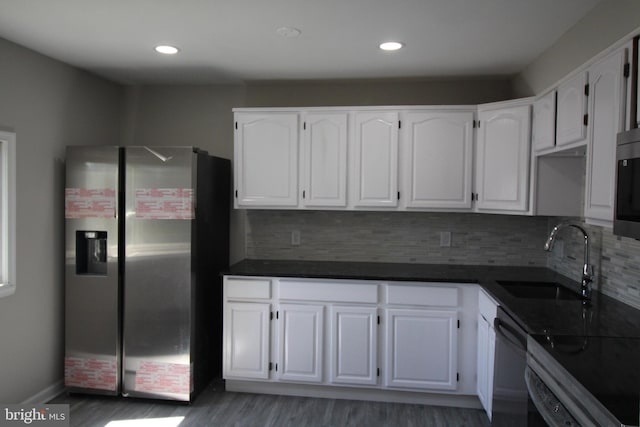 kitchen featuring a sink, dark countertops, appliances with stainless steel finishes, and white cabinets