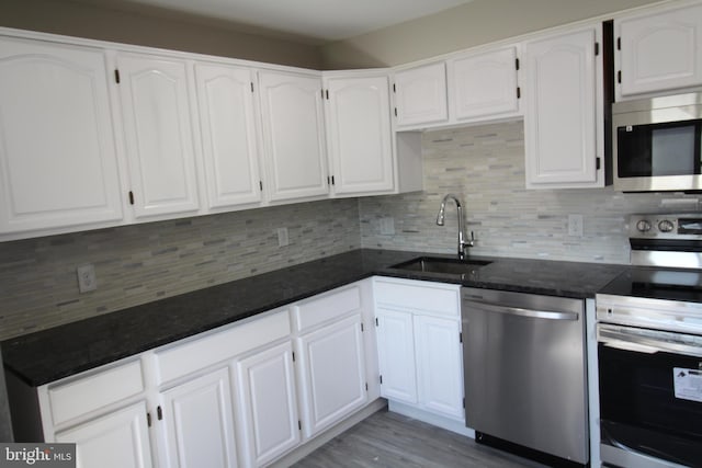 kitchen with a sink, stainless steel appliances, white cabinets, and decorative backsplash