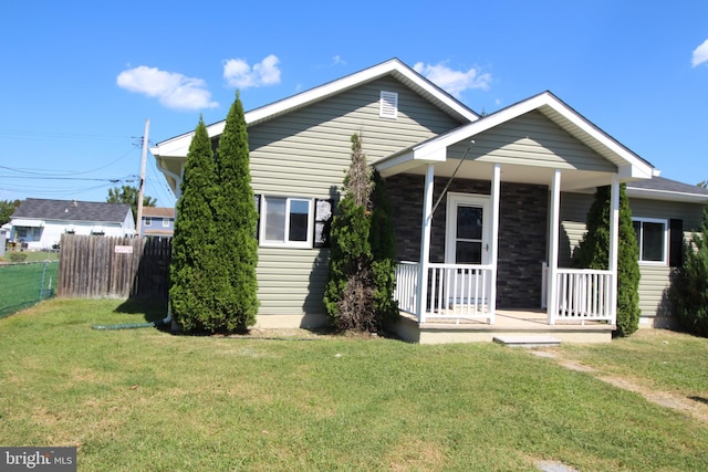 view of front facade with a porch, a front lawn, and fence