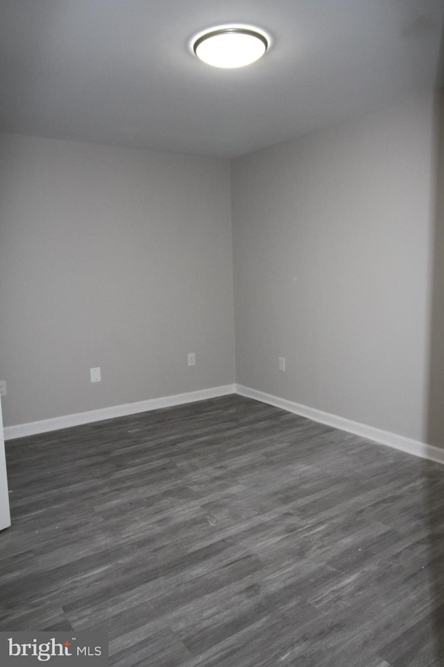 spare room featuring dark wood-type flooring and baseboards