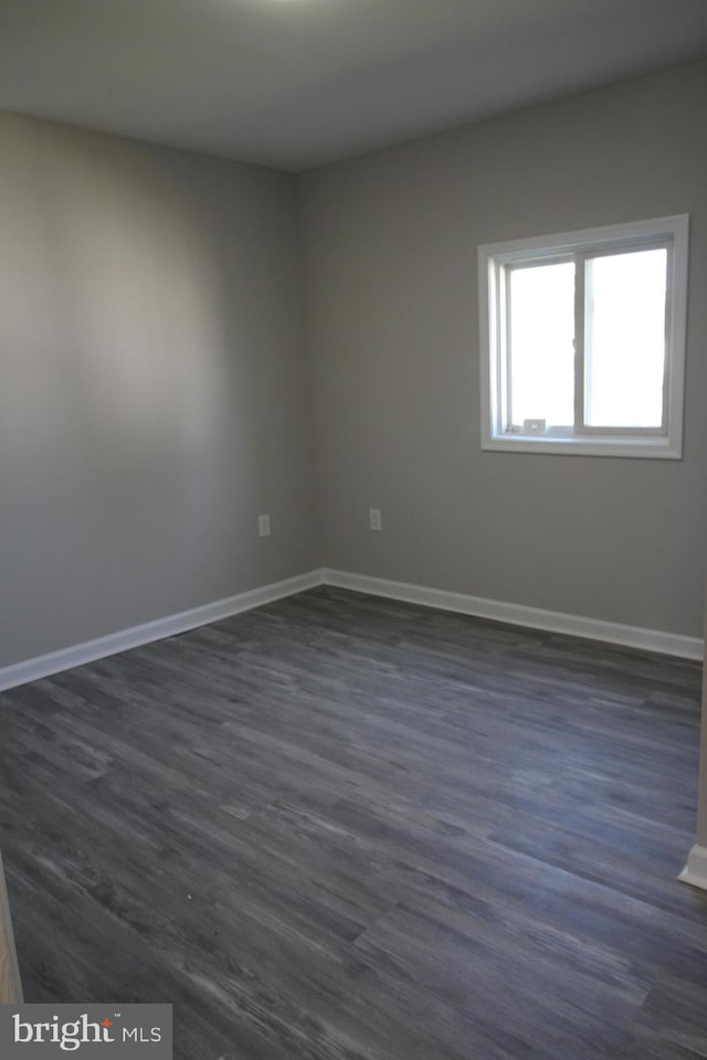 spare room with dark wood-type flooring and baseboards