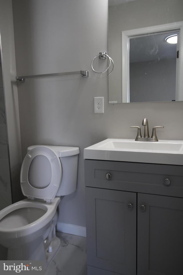 bathroom featuring baseboards, toilet, marble finish floor, and vanity