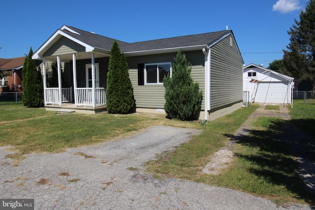 view of front of property featuring an outbuilding, a front lawn, a detached garage, covered porch, and crawl space