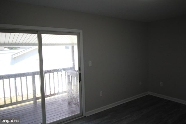 spare room featuring baseboards and dark wood-type flooring