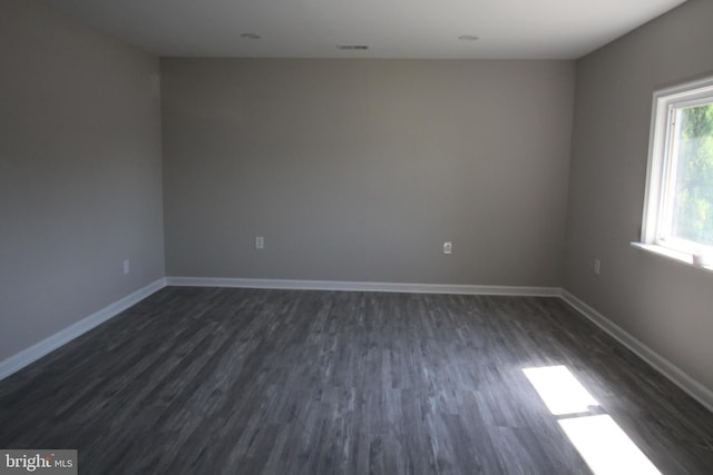 empty room featuring baseboards and dark wood-type flooring